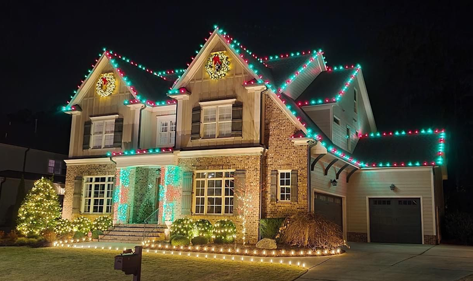 Home lit with red and green Christmas lights and wreaths